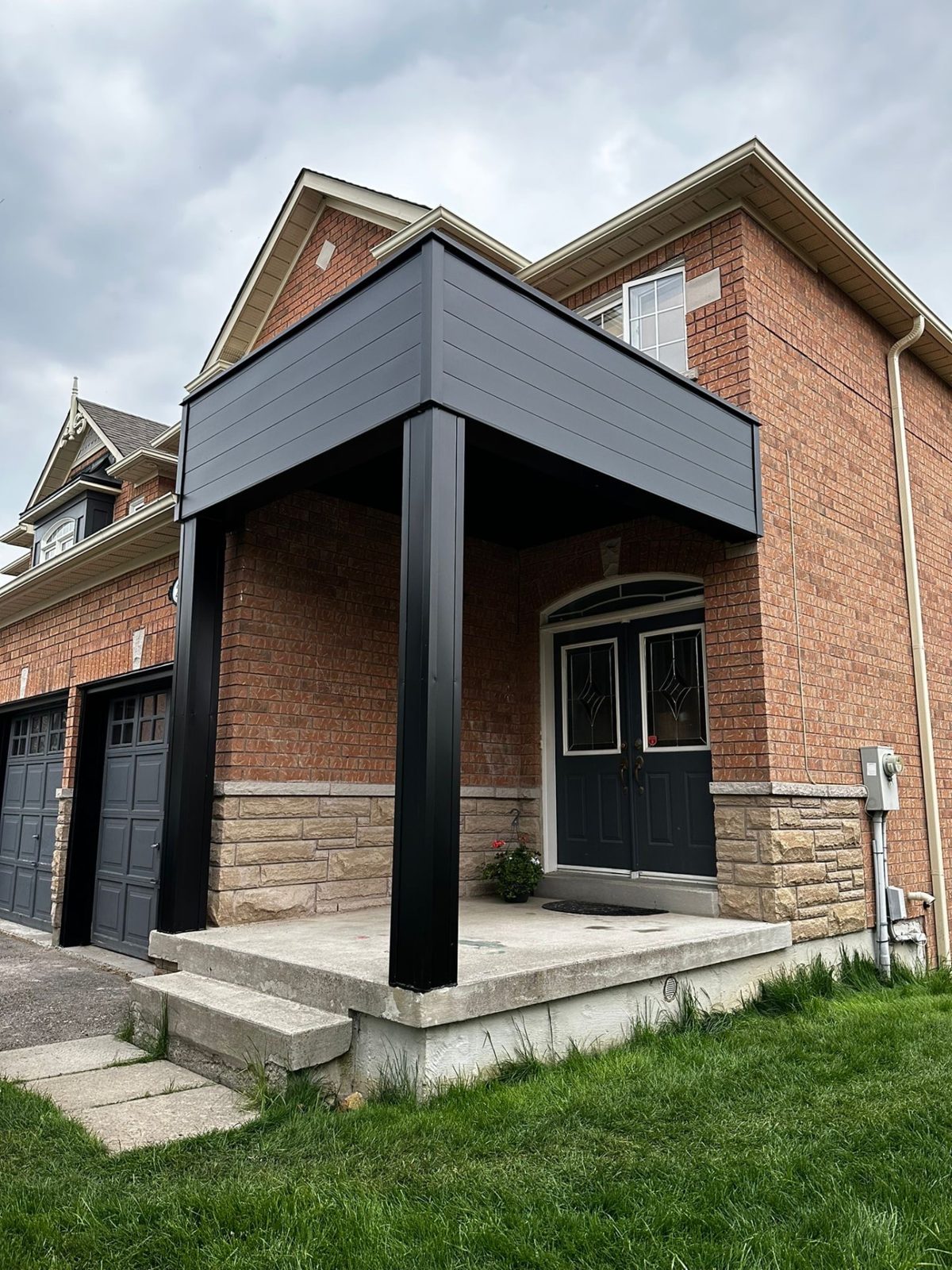Entrance posts and canopy wrapped in black aluminum